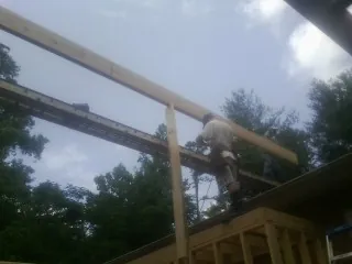Carpenter setting a ridge beam over a new addition frame — Ice Dam Removal by Roofing Brothers in Morrisonville