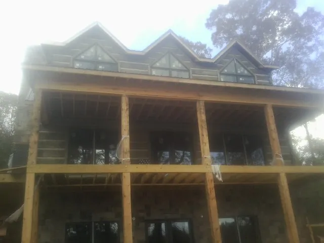 Dormers and porch framing on a large log home under construction — Roof Coating work by our crew in Morrisonville
