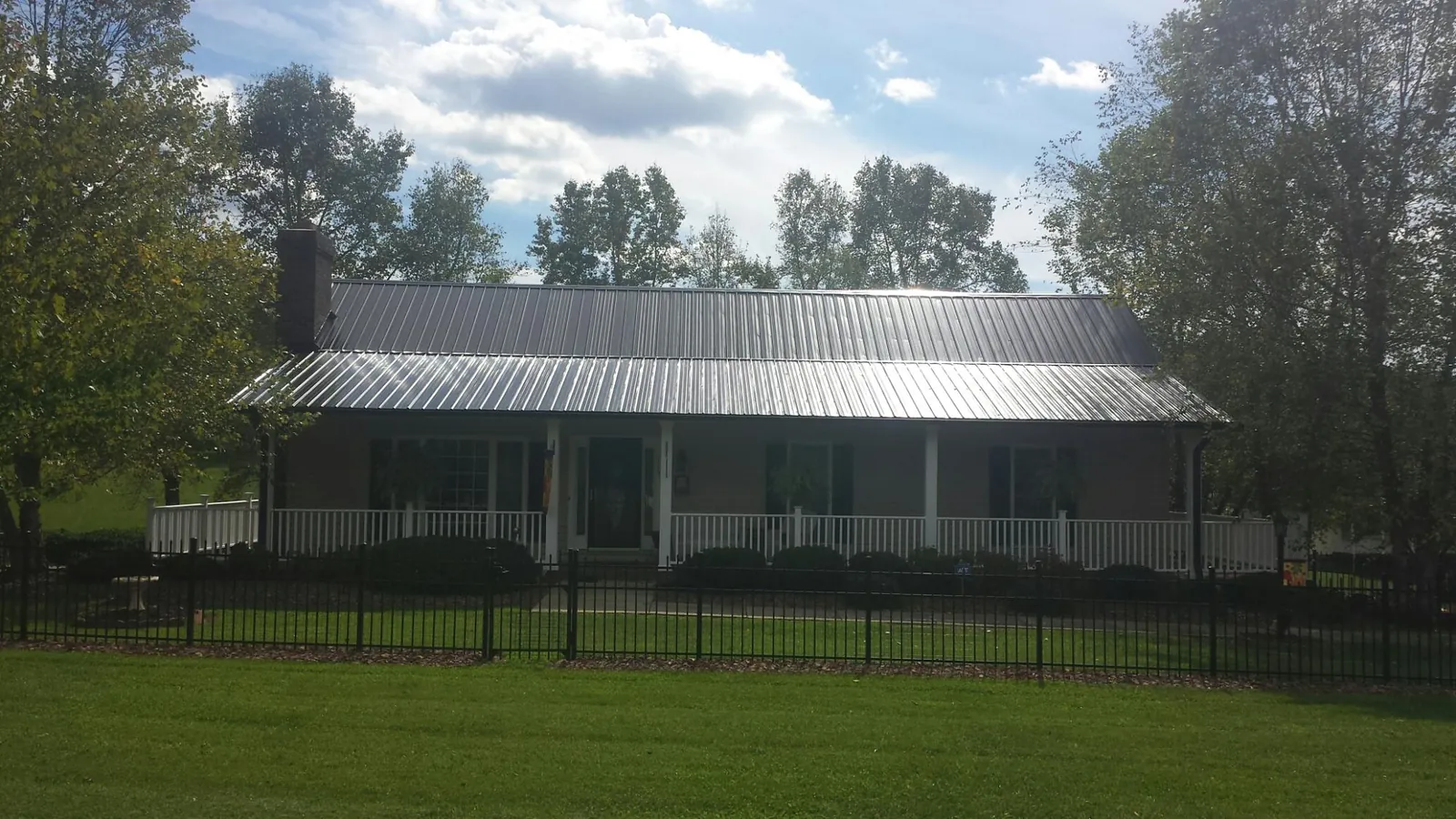 Gray metal roof on a brick ranch with a full width front porch — Gutter Guard Installation work by our crew in Morrisonville