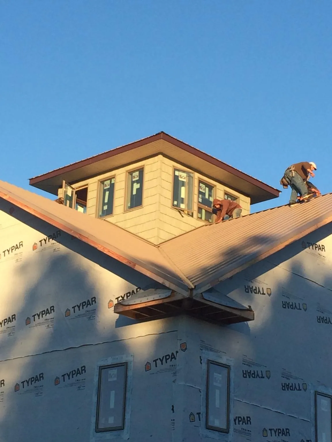Roofers working around a rooftop cupola on a new metal roof at sunset — Roof Waterproofing in Morrisonville by Roofing Brothers
